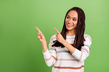 Photo of dreamy young afro american woman look point fingers empty space smile isolated on green color background