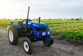 Blue farm tractor stands on field. Application of agricultural machinery in harvesting....