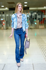 Blonde with long hair stands near the turnstiles at subway station. High quality photo