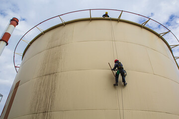 Male worker rope access height safety inspection of thickness storage oil and gas tank