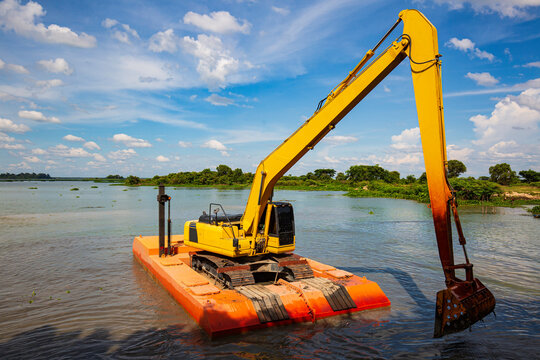 The yellow backhoe is working at the river floatin