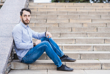 Portrait of a man businessman with a beard who sits on the steps