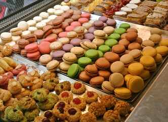 Bright assortment of the sweet french delights. So called petit fours: macaron, eclair and range of cookies. Different pastel colors. On display.   