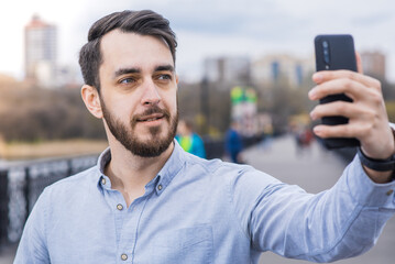 Portrait of a man businessman with a beard in a shirt who takes a selfie on a smartphone