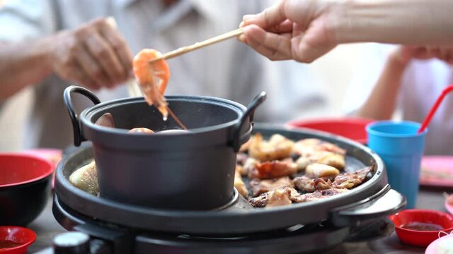 Shrimp seafood cooking on hot pot, delicious or tasty menu for party, fresh shrimp on chopsticks holding to dish