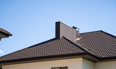 Brown corrugated metal profile roof installed on a modern house. The roof of corrugated sheet. Roofing of metal profile wavy shape. Modern roof made of metal. Metal roofing.