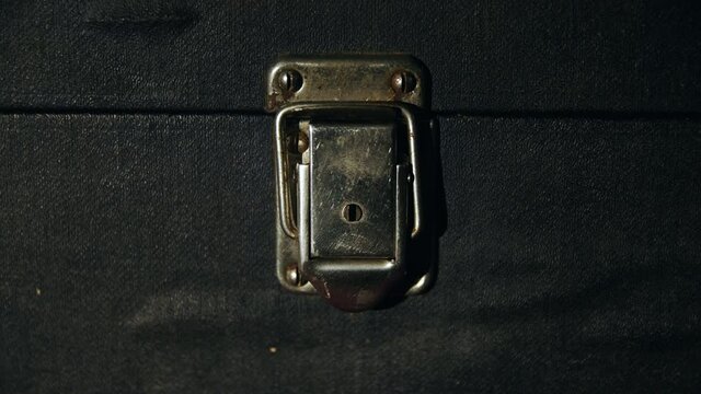 Caucasian man by hand closes an old vintage metal rusty lock on a dirty antique suitcase close up