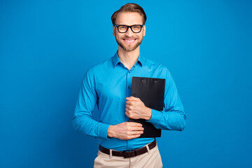 Photo of young business man happy positive smile hold clipboard organizer isolated over blue color background
