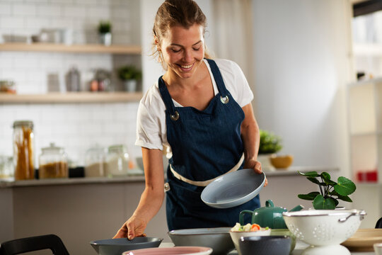Young woman setting a table for lunch. Smiling happy woman preparing a delicious food..