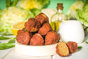 Middle eastern or Arabic dish, roasted chickpeas falafel patties with garlic yogurt sauce, lettuce and fresh green vegetables copy space