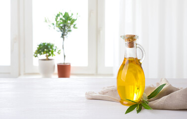 Olive oil bottle on table against sunlit kitchen window background