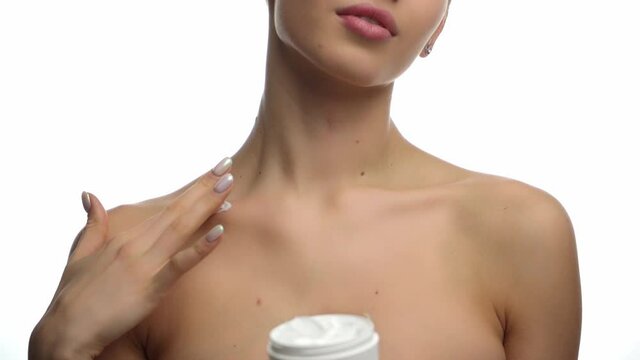 cropped view of woman applying cosmetic cream on clavicle isolated on white