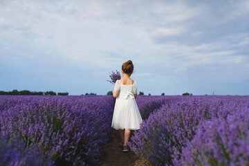 Fototapeta na wymiar girl walking away with lavender bouquet