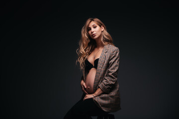 Fototapeta premium Young beautiful pregnant woman in jacket on black background
