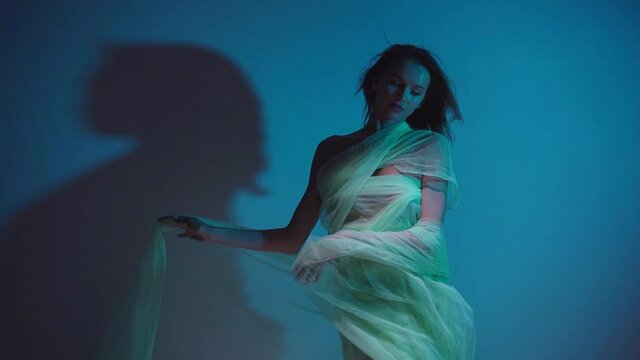 slow motion of young woman in chiffon dress on blue