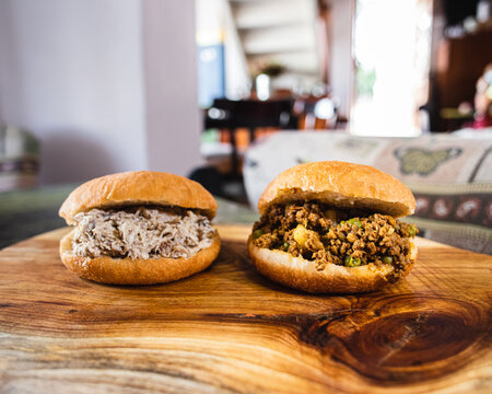 Bokeh photo of chicken mayo and minced beef burger on wooden cutting board