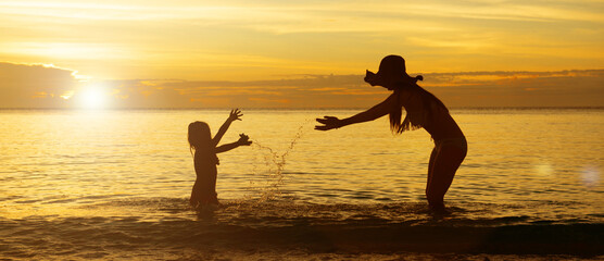 Fototapeta na wymiar 夕暮れのビーチで遊ぶ母と娘