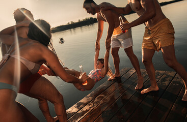 Fototapeta na wymiar Friends having fun enjoying a summer day swimming and jumping at the lake.