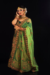 Fototapeta na wymiar Woman in bridal green sari and gold jewelry looking down