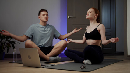 Obraz premium A girl and her boyfriend are watching meditation lessons on a laptop and trying to relax