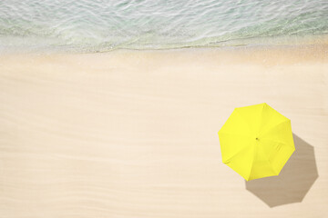 Yellow umbrella on tropical sand beach. Top and aerial view. Ocean coastline. Drone photo. Background