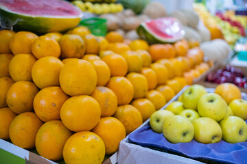 Colorful fruit stand with oranges, sliced watermelon, apples, and more