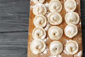 Raw meat dumplings on wooden board on table