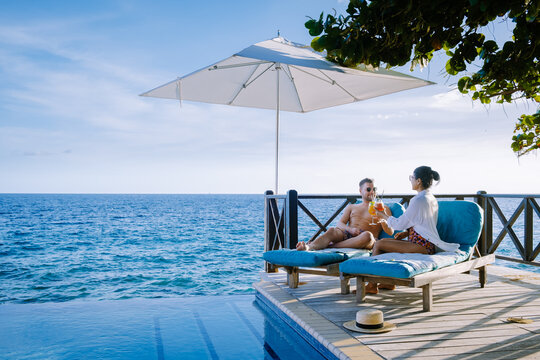 Curacao, couple man and woman mid age relaxing by the swimming pool during vacation, men and girl by pool in Curacao during holiday at a tropical island luxury vacation