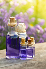 Glass bottle of Lavender essential oil on wood table and flowers field. Lavendula oleum