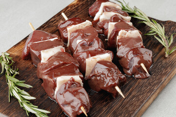 Raw beef liver on skewers on board