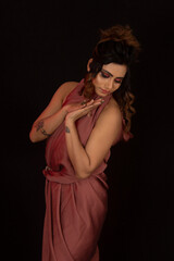 Obraz premium Young Indian girl in western brown dress. Looking down. Black background.
