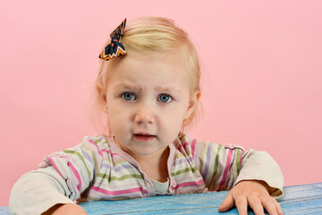 A not very happy child sits at the table and looks somewhere.