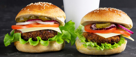 Cheeseburgers and cup of coffee on a black stone background. Banner.Hamburger with cheese. Burger isolated. Tasty Dinner.Copy space