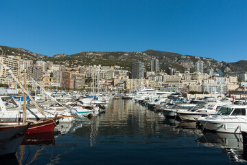 Fototapeta na wymiar Luxury yachts in the Monaco harbor with large apartment complexes on background. Mediterranean yacht marina in Monaco sea port, Monaco and Monte Carlo principality. High quality photo