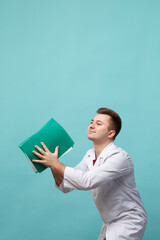 Young doctor with a green folder in hands isolated on a blue background.