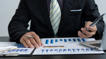 Business analysts create graphs of investment costs, real estate and other tax systems on their desks with laptops.