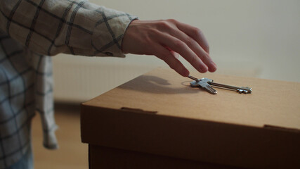 The woman puts the keys on the box and put the pot with the plant on the sill