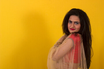 Fototapeta premium Young Indian female model in Ghagra Choli and long hair looking at camera