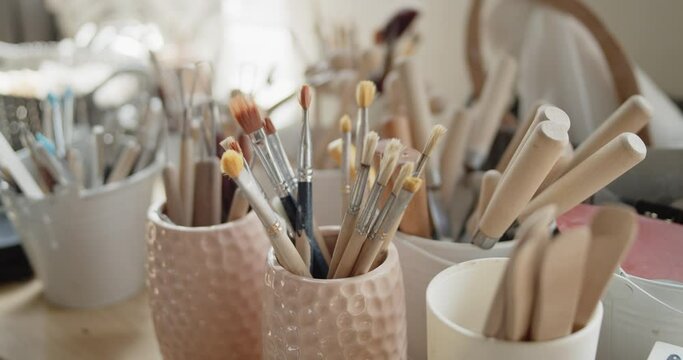 Set of tools for crafting, texturizing or sculpting clay in pottery workshop. Bunch of brushes, knives and other wooden tools for handwork with clay.