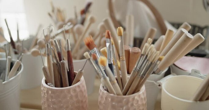 Set of tools for crafting, texturizing or sculpting clay in pottery workshop. Bunch of brushes, knives and other wooden tools for handwork with clay.
