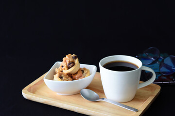 coffee and cookies on wood tray, on black background with big copy space