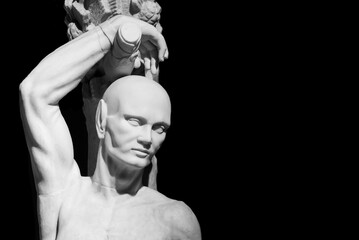 Black and white photo of ancient roman sculpture of a bold man tied to a pole