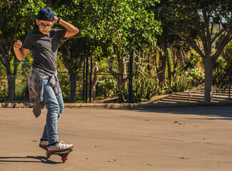 Fototapeta premium Caucasian boy with cap skating with his skateboard in a skate park