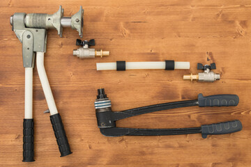 on a dark wooden background lies a tool for the installation of XLPE pipelines and a pipe with accessories