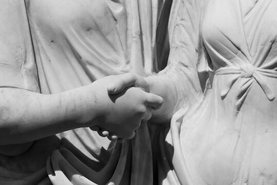 Black and white photo in close-up of  two ancient roman sculptures shaking hands
