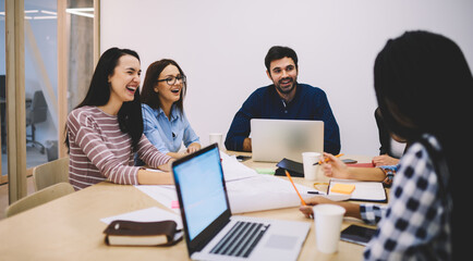 Laughing colleagues with laptops talking during workday