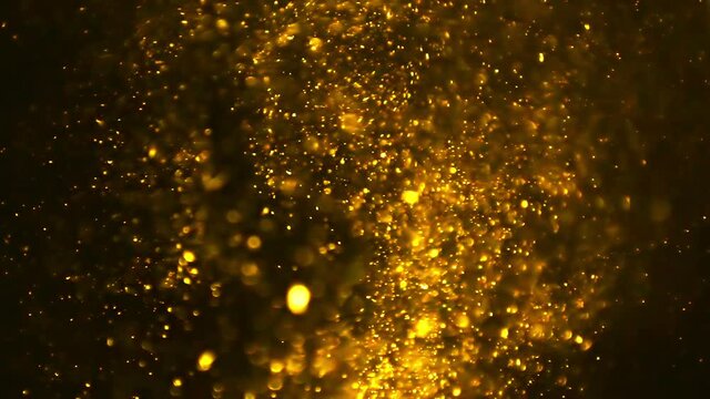 Abstract golden dust particles in flying on black background