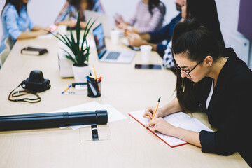 Concentrated woman taking notes on meeting