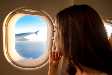 Fototapeta na wymiar Young woman looking through window in airplane.Girl sitting in airplane near window.