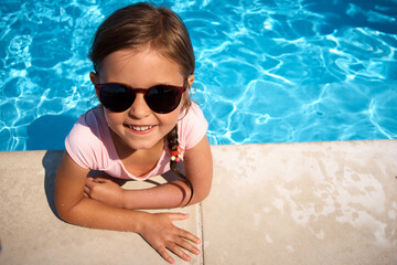 Happy little girl by the pool. Summer vacation.